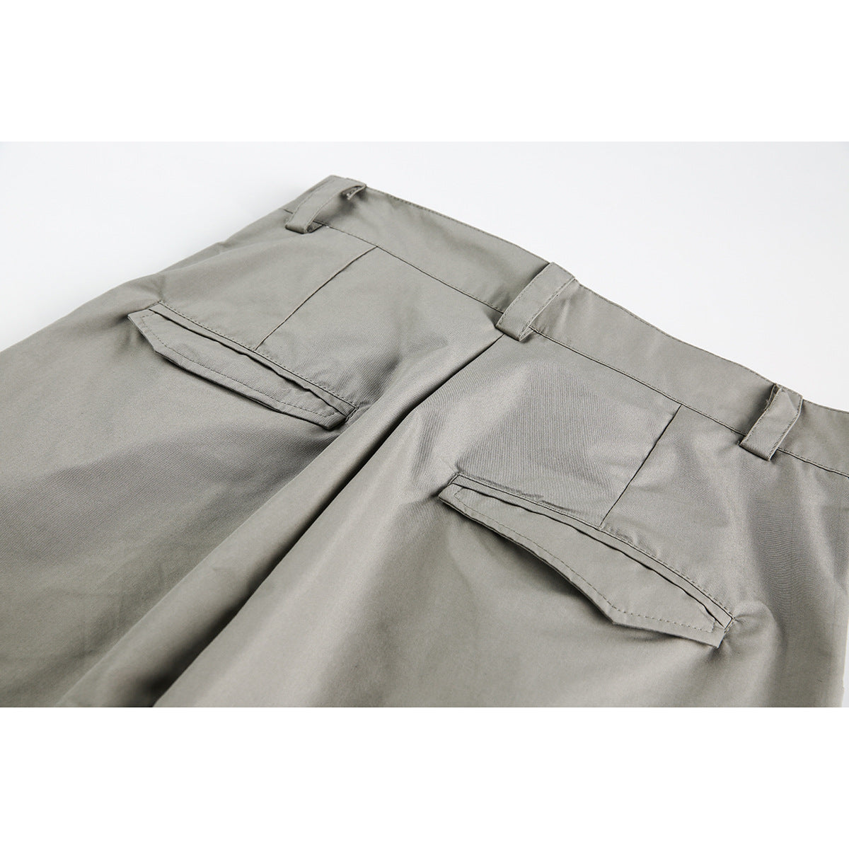 Close-up of gray trousers showing the rear waistband, belt loops and two flap welt pockets.