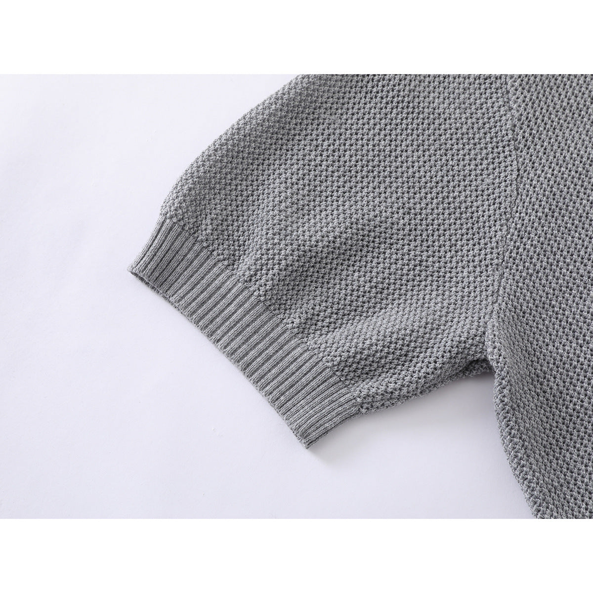 Close-up of the gray knit polo shirt's short sleeve and ribbed cuff.