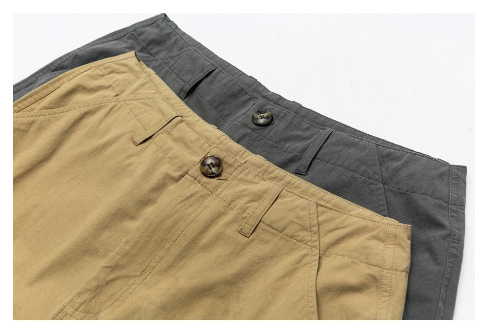 Close-up of khaki and gray cargo shorts waistbands showing horn-style buttons, belt loops and pocket stitching