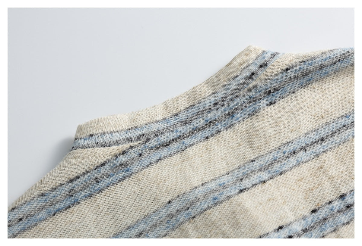 Close-up of a curved stitched seam on cream fabric with irregular blue and charcoal stripes.