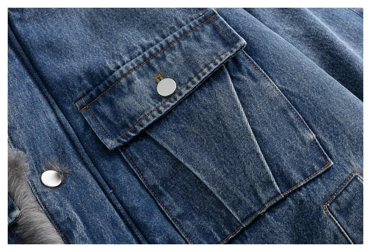 Close-up of a blue denim jacket's flap pocket with a metal snap and orange stitching.