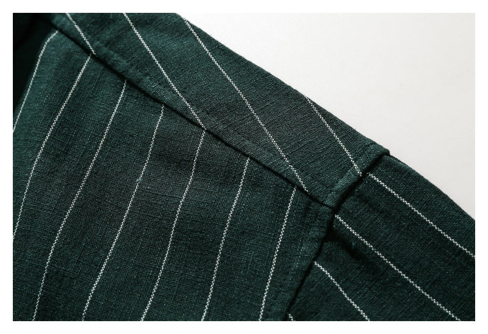 Close-up of the dark green shirt's striped shoulder seam and collar edge.