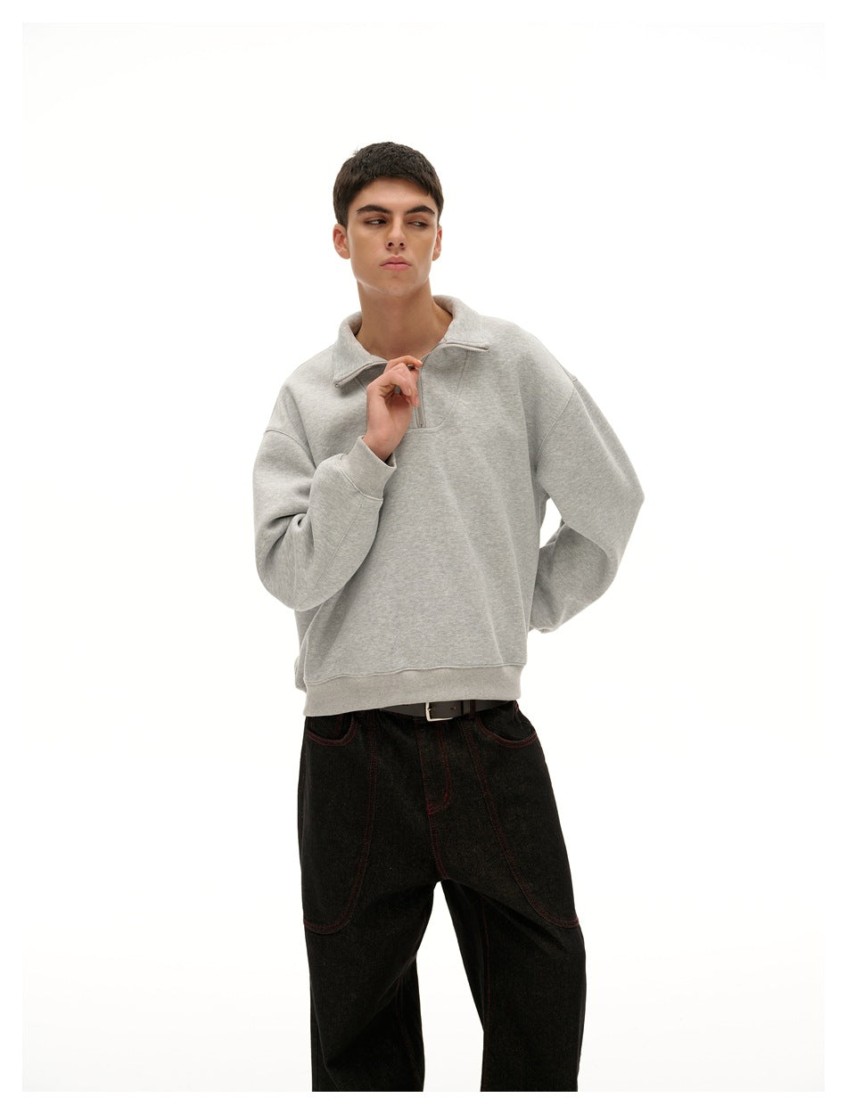 Model wearing a light gray quarter-zip pullover with a folded collar and ribbed cuffs and hem, shown from the front.