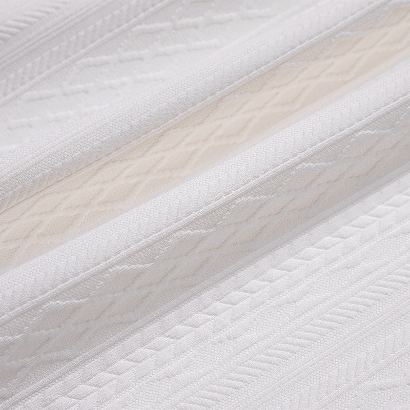 Extreme close-up of the white shirt's raised geometric fabric pattern and seams.