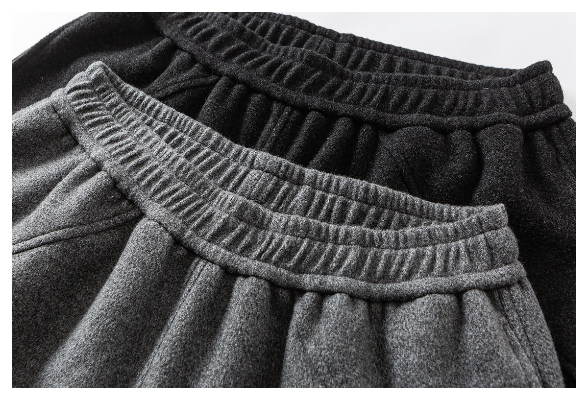 Close-up of gray and black pants, highlighting their gathered waistbands and textured fabric.