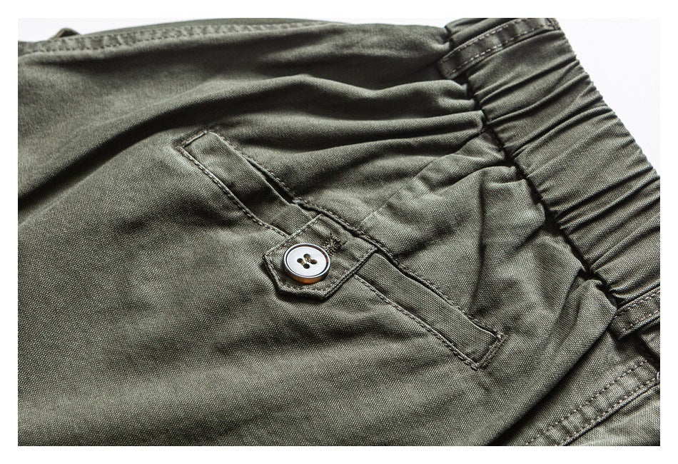 Close-up of an olive trouser pocket with a button tab beside the elastic waistband.