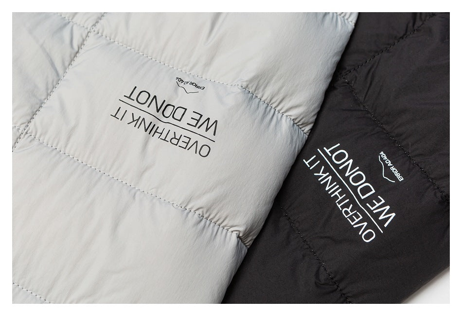 Close-up of light gray and black quilted jacket panels with the phrase “OVERTHINK IT WE DON'T” printed on them.