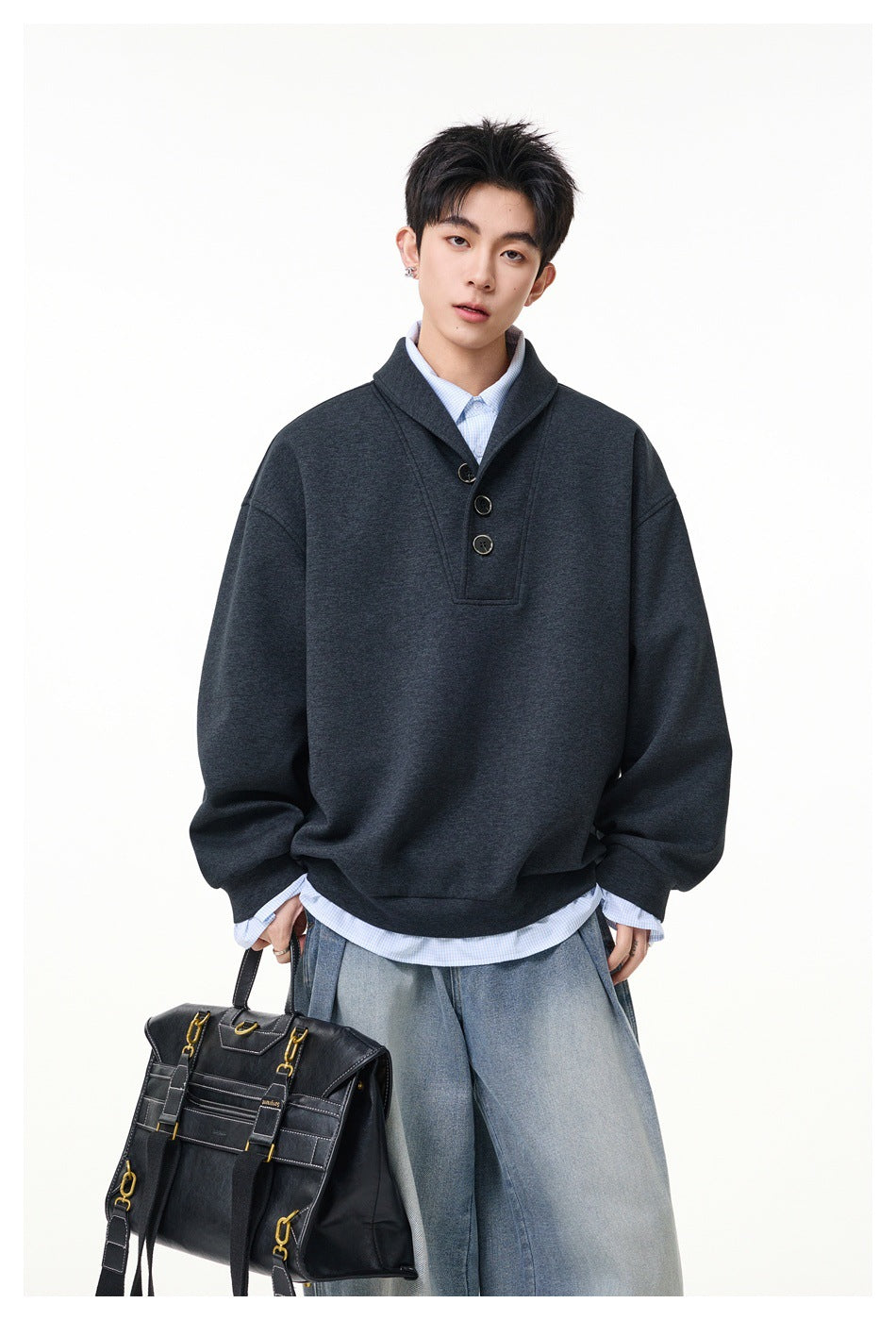 Model wearing a charcoal oversized pullover with a wide collar and three-button placket, styled with jeans.