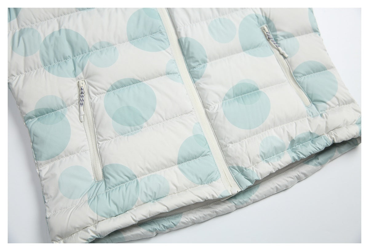 Close view of a white quilted puffer jacket with pale aqua circles, a central zipper and two zip pockets.