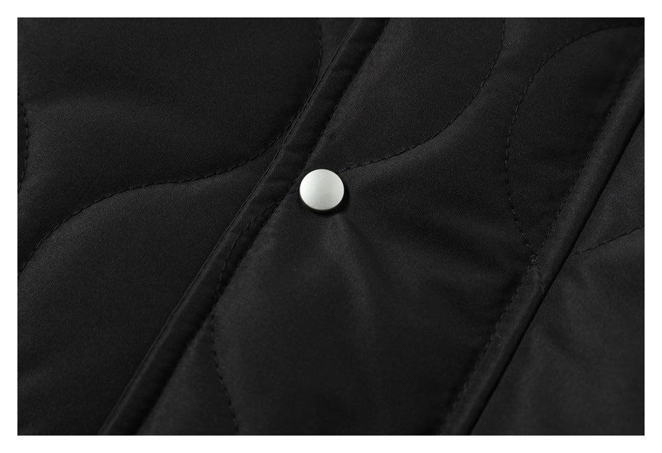 Close-up of a silver snap on the black jacket’s quilted front placket.