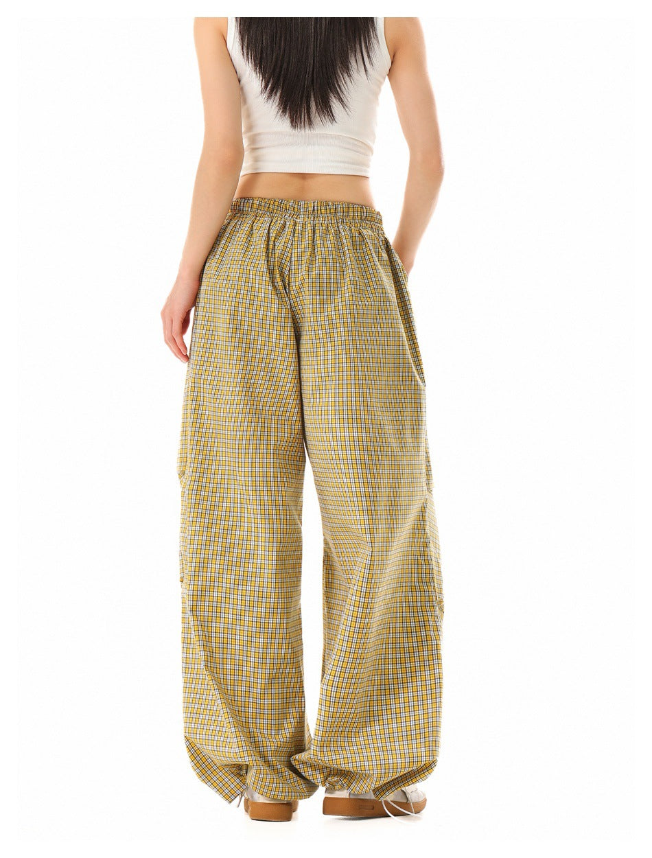 Back view of a model wearing loose, wide-leg yellow plaid pants with an elastic waist.
