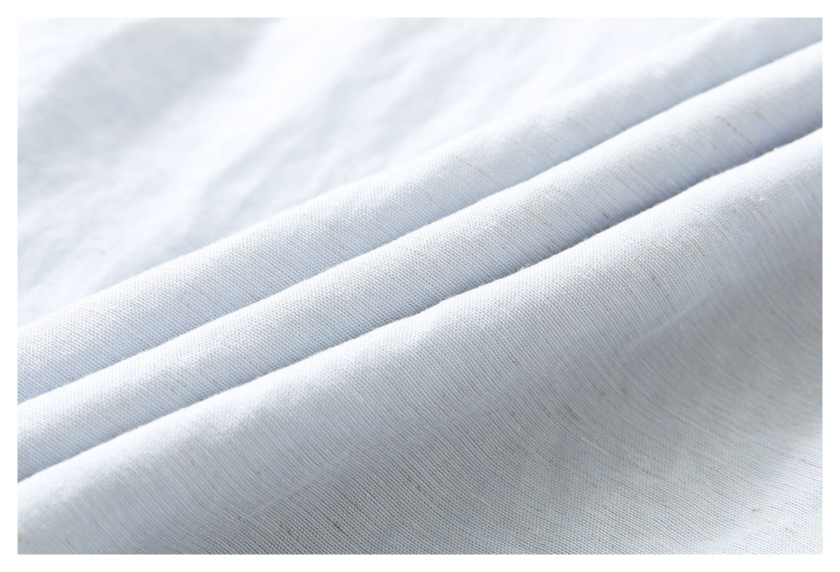 Close-up showing the fine woven texture and folds of pale blue-gray shirt fabric.
