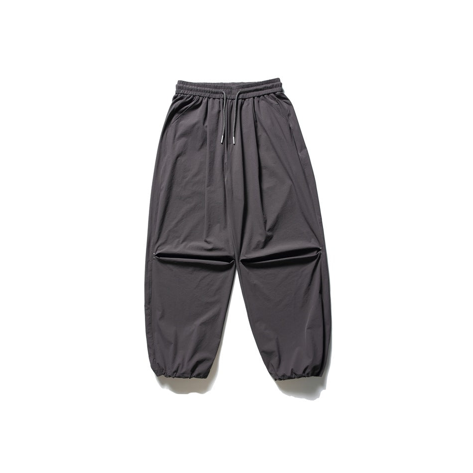 Front view of charcoal-gray wide-leg pants with an elastic drawstring waist, horizontal knee openings and gathered cuffs.