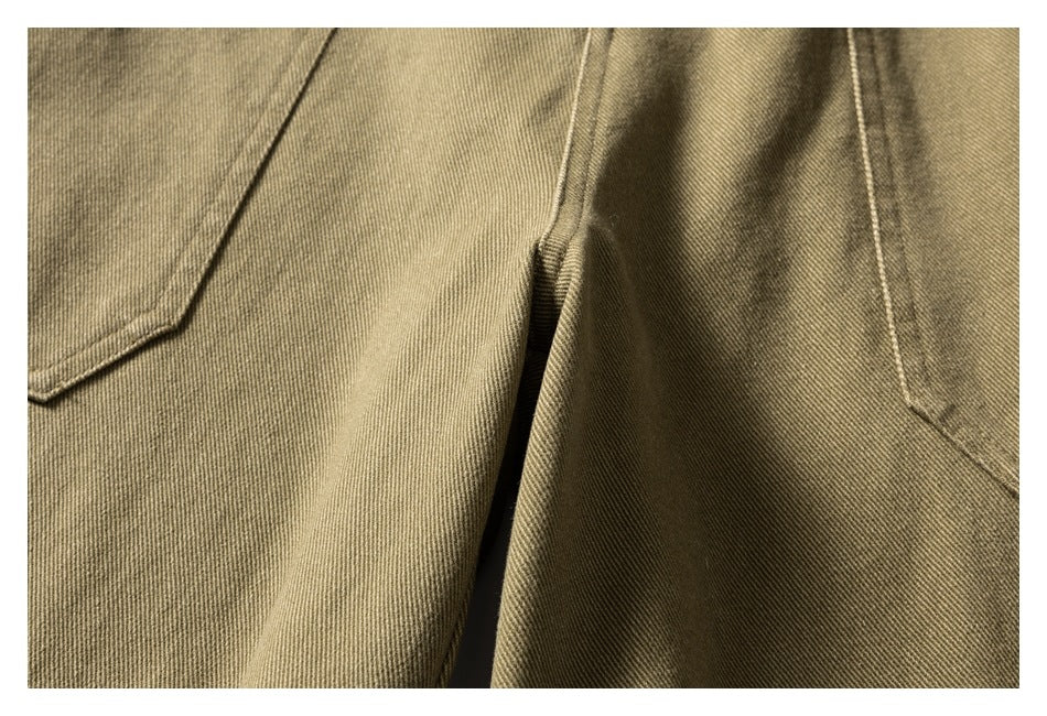 Close-up of khaki trousers showing overlapping seams and pocket edges.