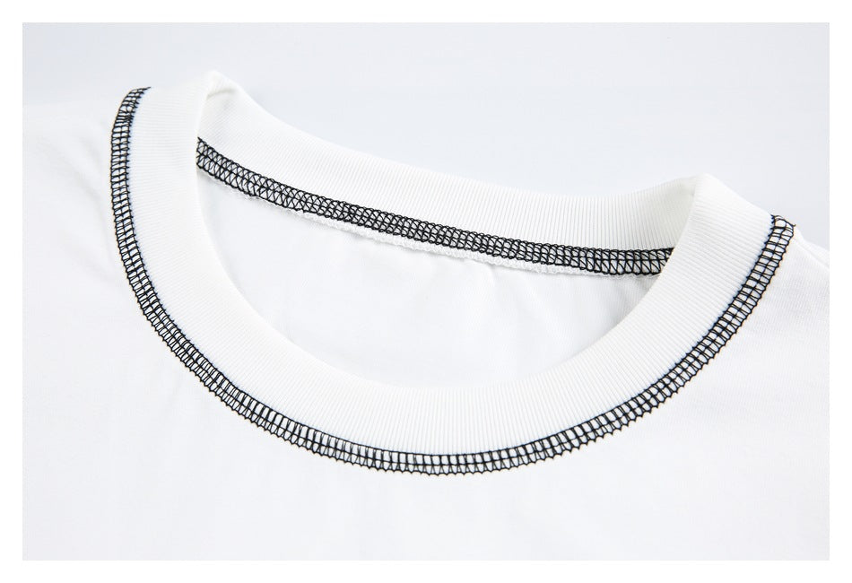 Close-up of a white T-shirt's ribbed crew neck with black contrast stitching.