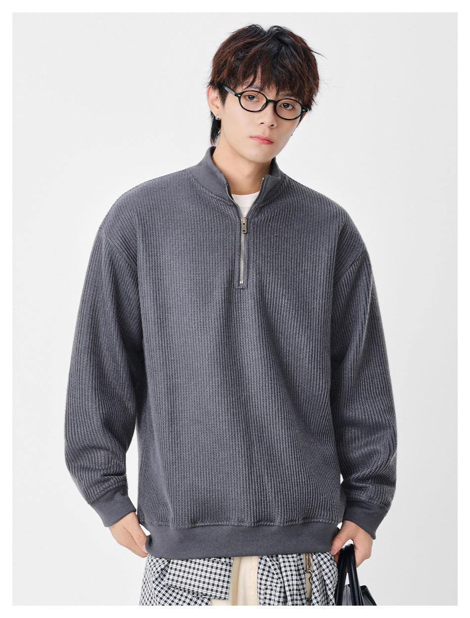 Front view of a model wearing an oversized charcoal gray textured quarter-zip sweater with ribbed trim.