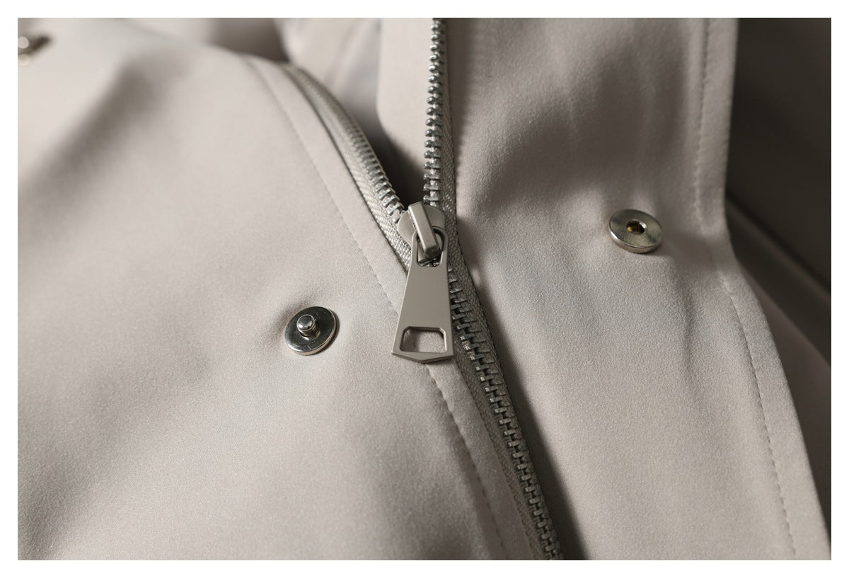 Close-up of the taupe trousers' zipper fly and metal snap fasteners.
