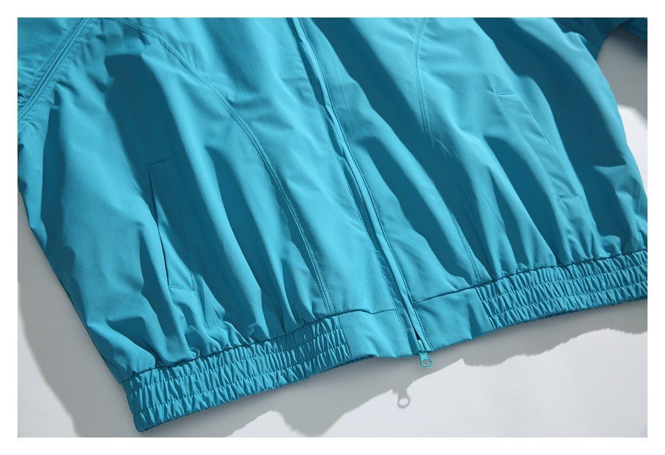 Close view of the turquoise jacket’s front zipper, hand pockets and gathered elastic hem.