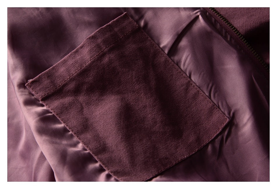 Close-up of a mauve jacket's rectangular pocket against smooth mauve lining, with zipper visible.