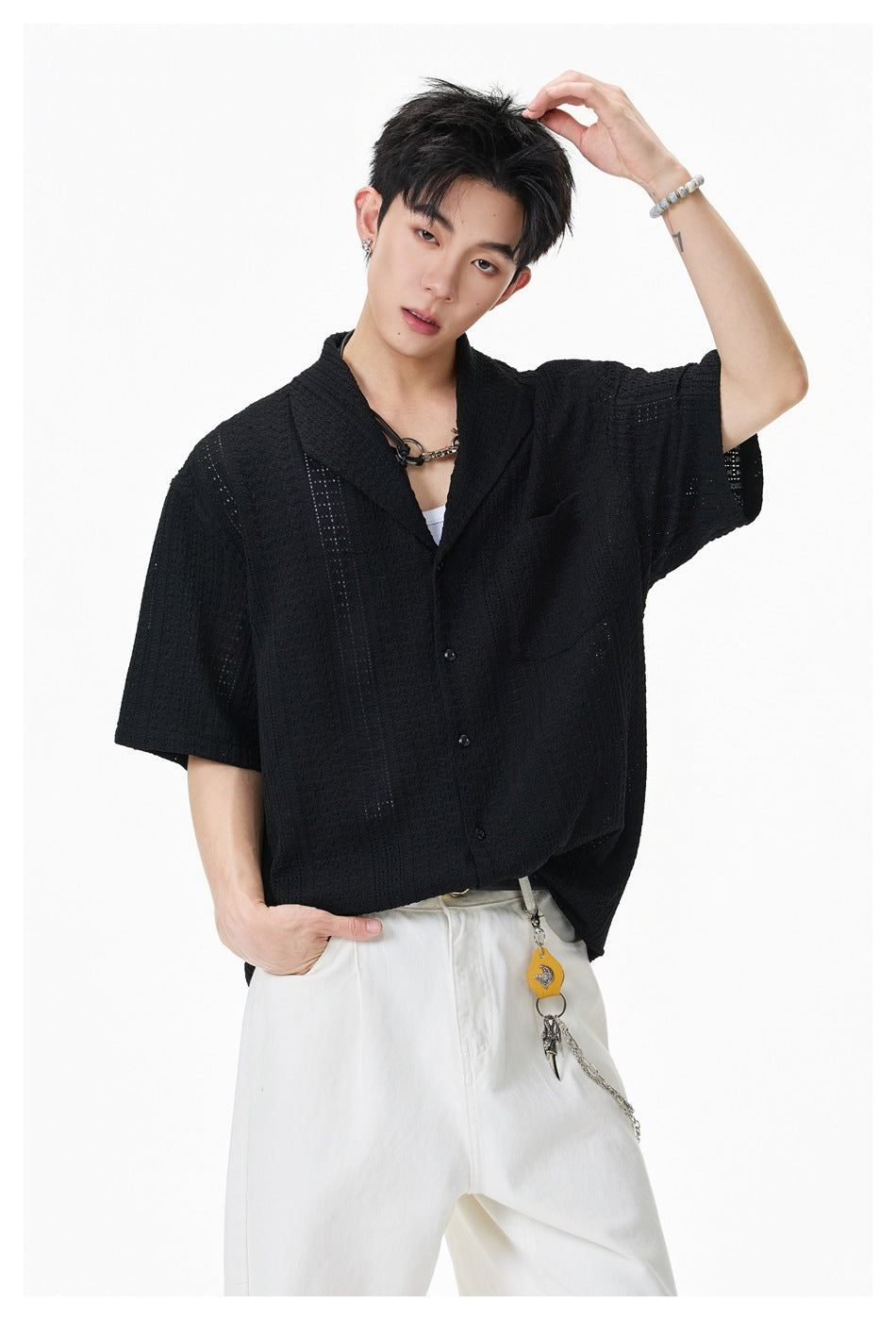 Model wearing a black short-sleeve button-up shirt with a shawl collar, openwork texture, and chest pocket.