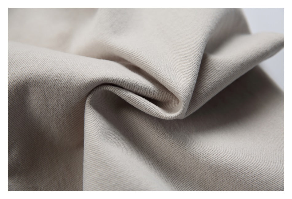Close-up of beige trouser fabric folded to show its surface and drape.