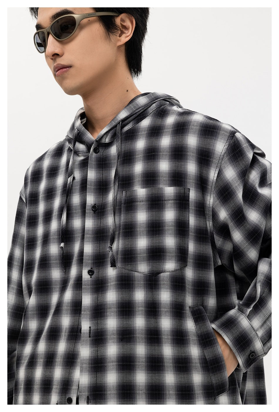 Model wearing a black-and-white plaid hooded button-up shirt with a chest pocket and drawstrings.