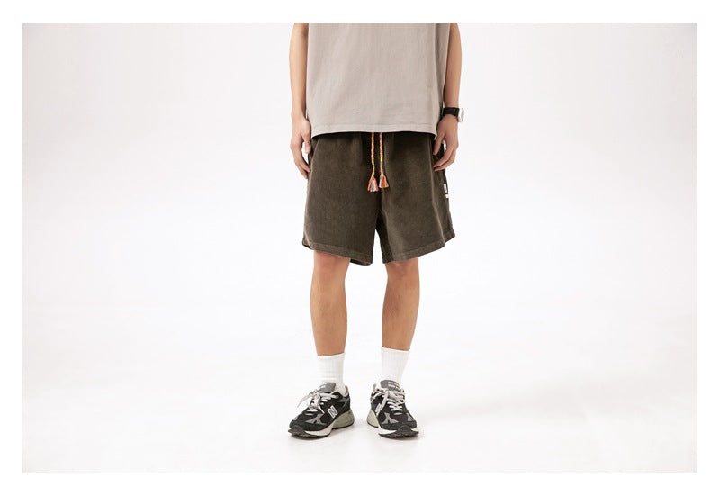 Cropped model wearing dark olive knee-length shorts with a colorful braided drawstring, shown from the front.