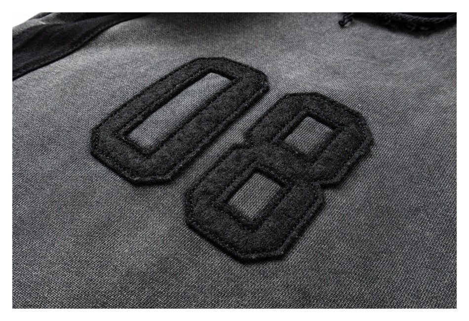Close-up of a raised black “08” appliqué on charcoal gray fabric.