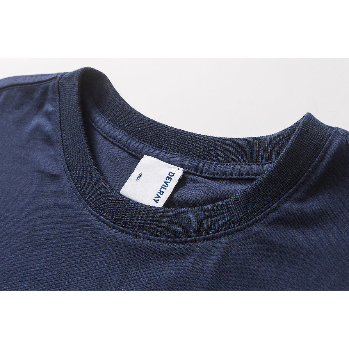 Close-up of a navy T-shirt's ribbed crew neck and sewn-in white DEVILRAY label.