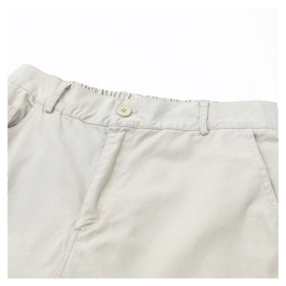 Close-up of light beige pants showing the buttoned waistband, belt loops, and front pockets.