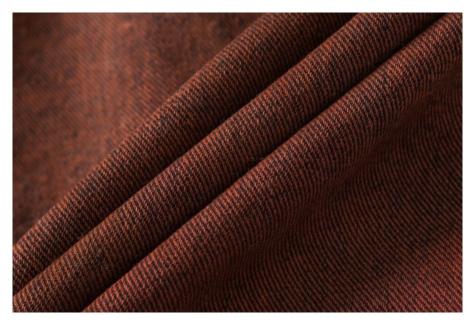 Close-up of dark rust-brown fabric folded to show its fine diagonal weave.