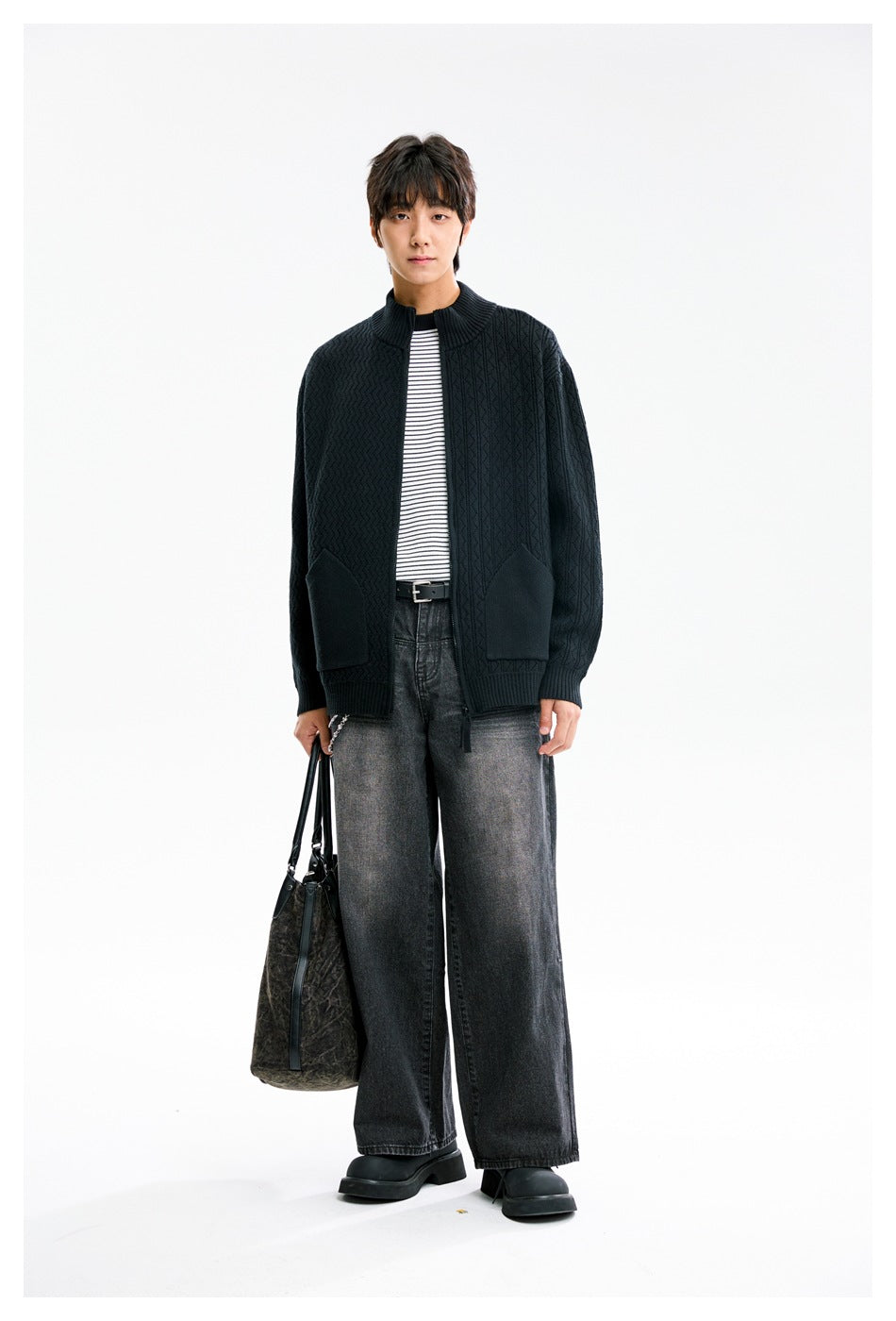 Full-length front view of a model wearing a dark patterned zip cardigan with a stand collar and patch pockets.