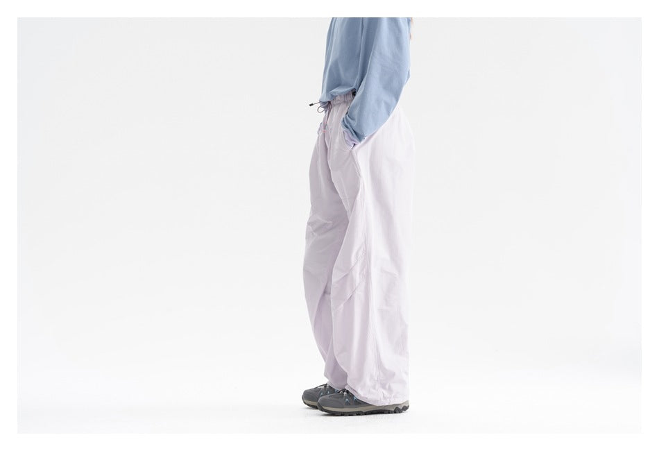 Side view of a model wearing loose pale lavender pants with a light blue top.