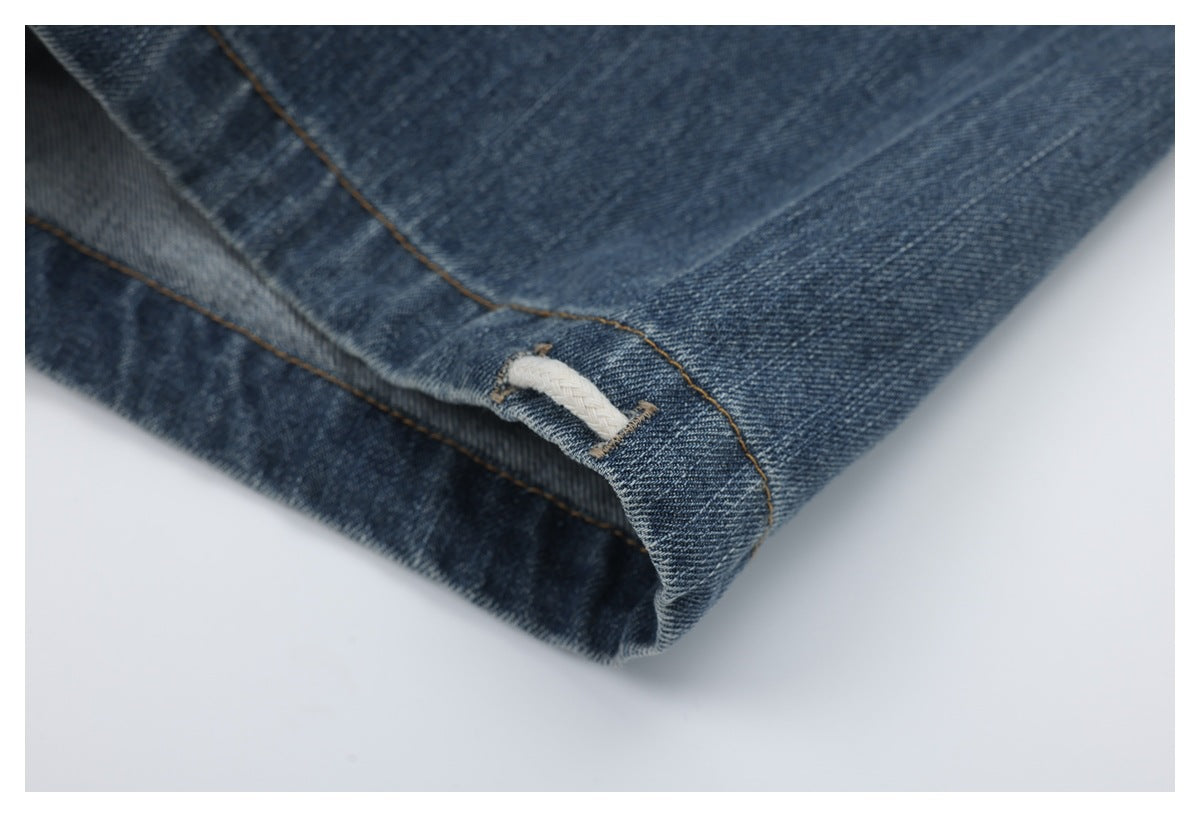 Close-up of blue denim with brown stitching and a small white loop at a folded edge.