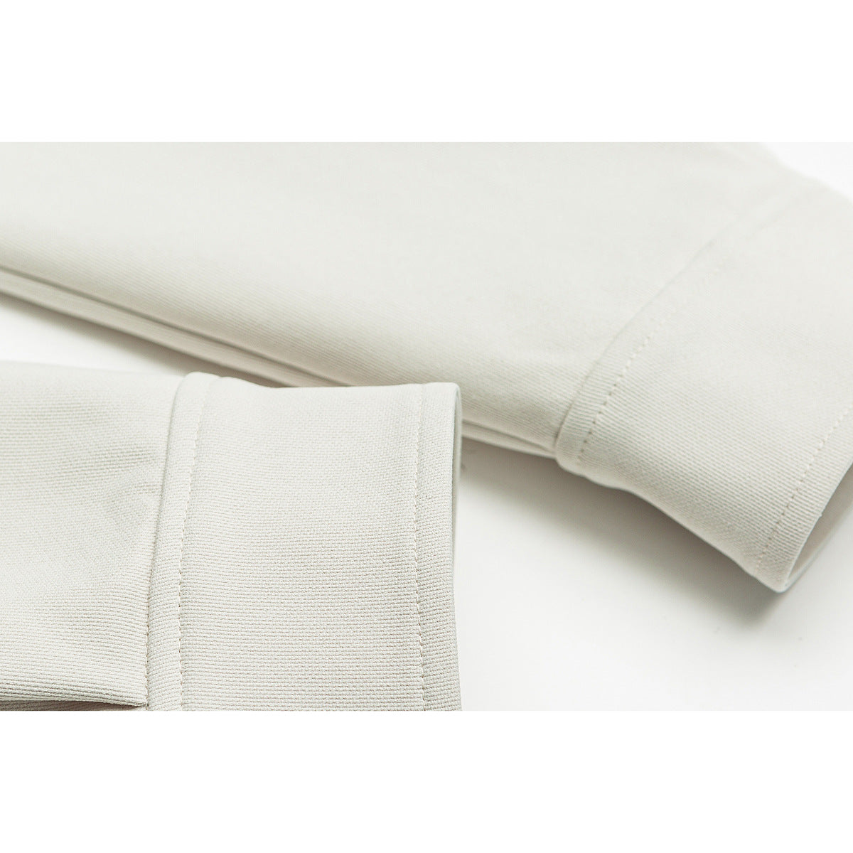 Close-up of off-white jacket sleeves and wide cuffs with visible stitching.
