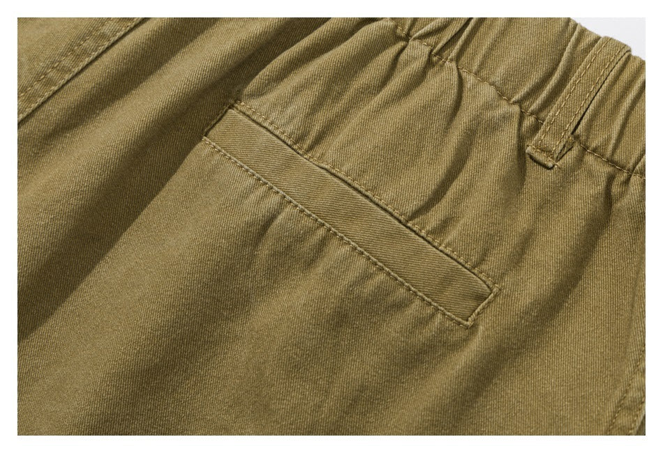 Close-up of an olive-khaki shorts pocket and elastic waistband stitching.