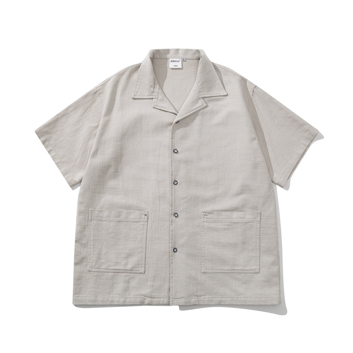 Light gray short-sleeve camp-collar button shirt with two large patch pockets, flat lay front view