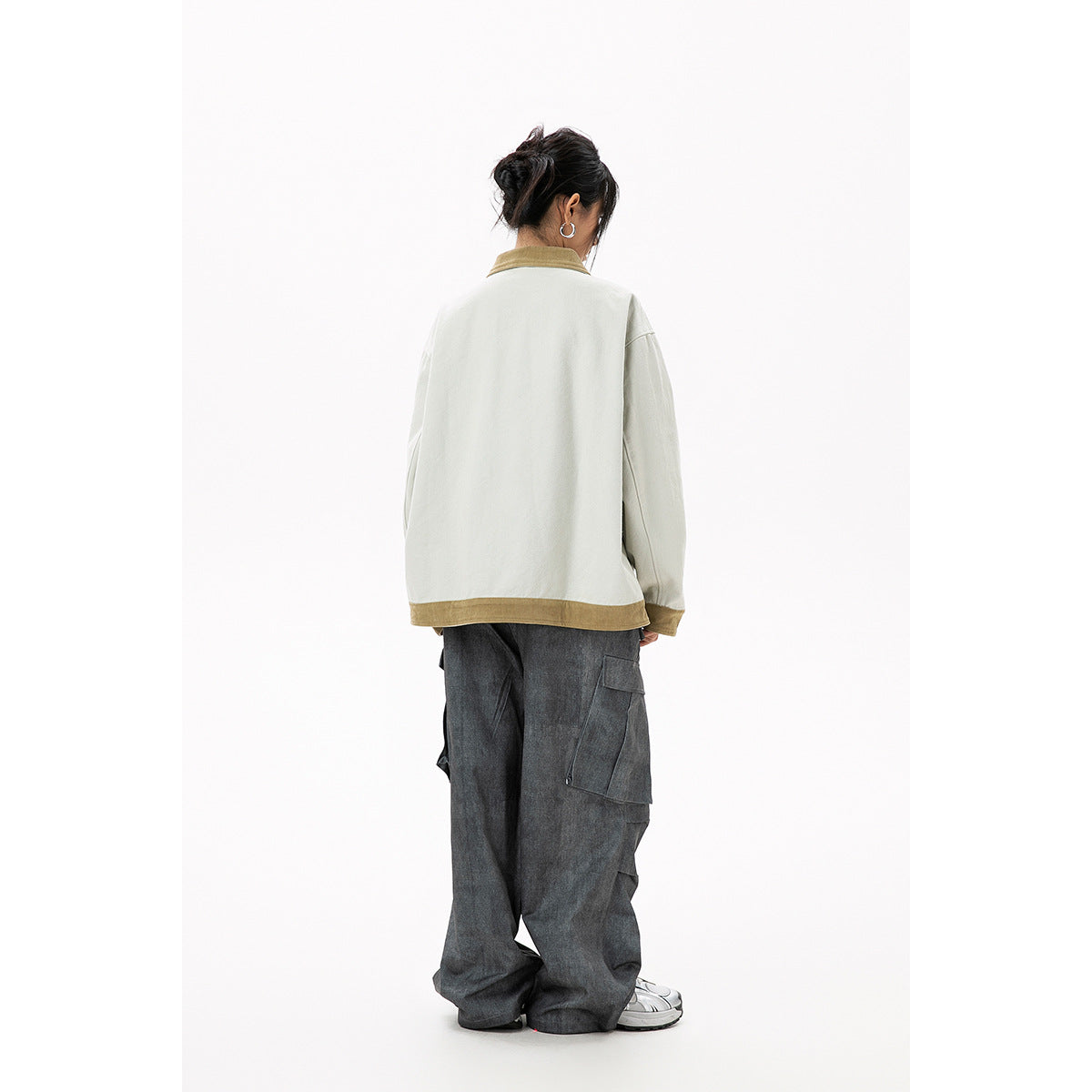 Back view of a model wearing a pale gray oversized jacket with tan collar and hem trim, and dark cargo pants.