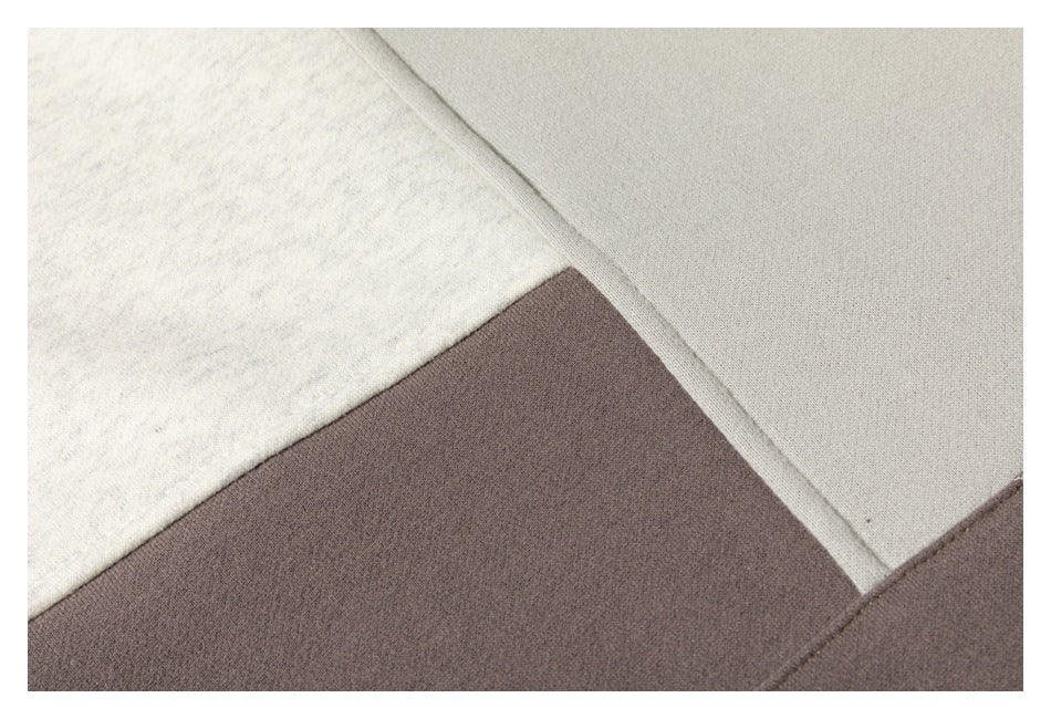 Close-up of cream and taupe sweatshirt panels meeting at an angled seam.