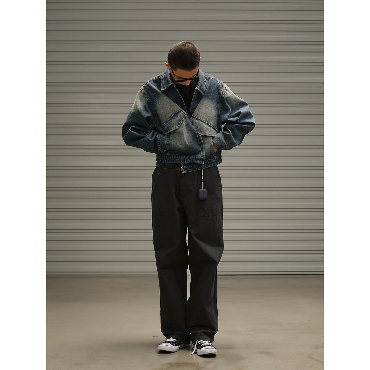 Full-length model wearing a roomy faded blue denim jacket with flap pockets, black trousers, and sneakers.