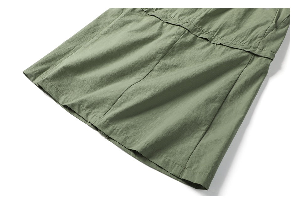 Cropped view of the gray-green garment's hem and stitched panel seams.