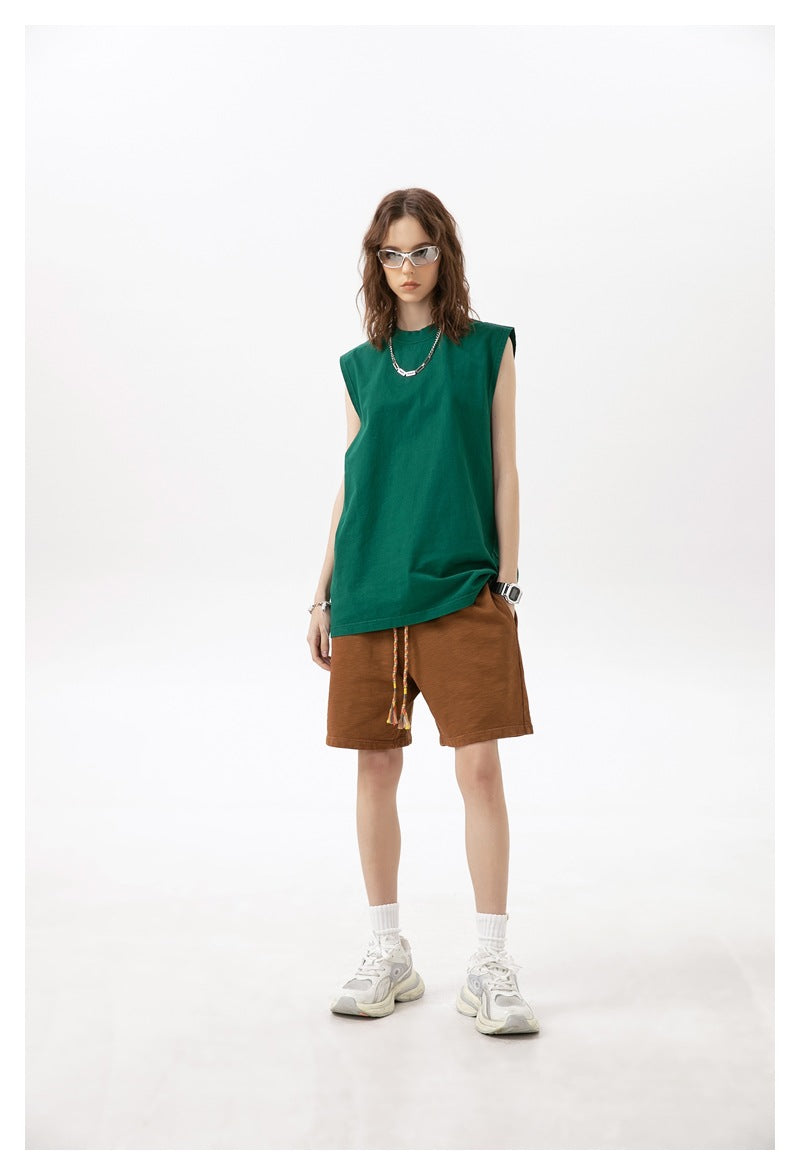 Model wearing rust-brown drawstring shorts with a green sleeveless top, white socks and sneakers.