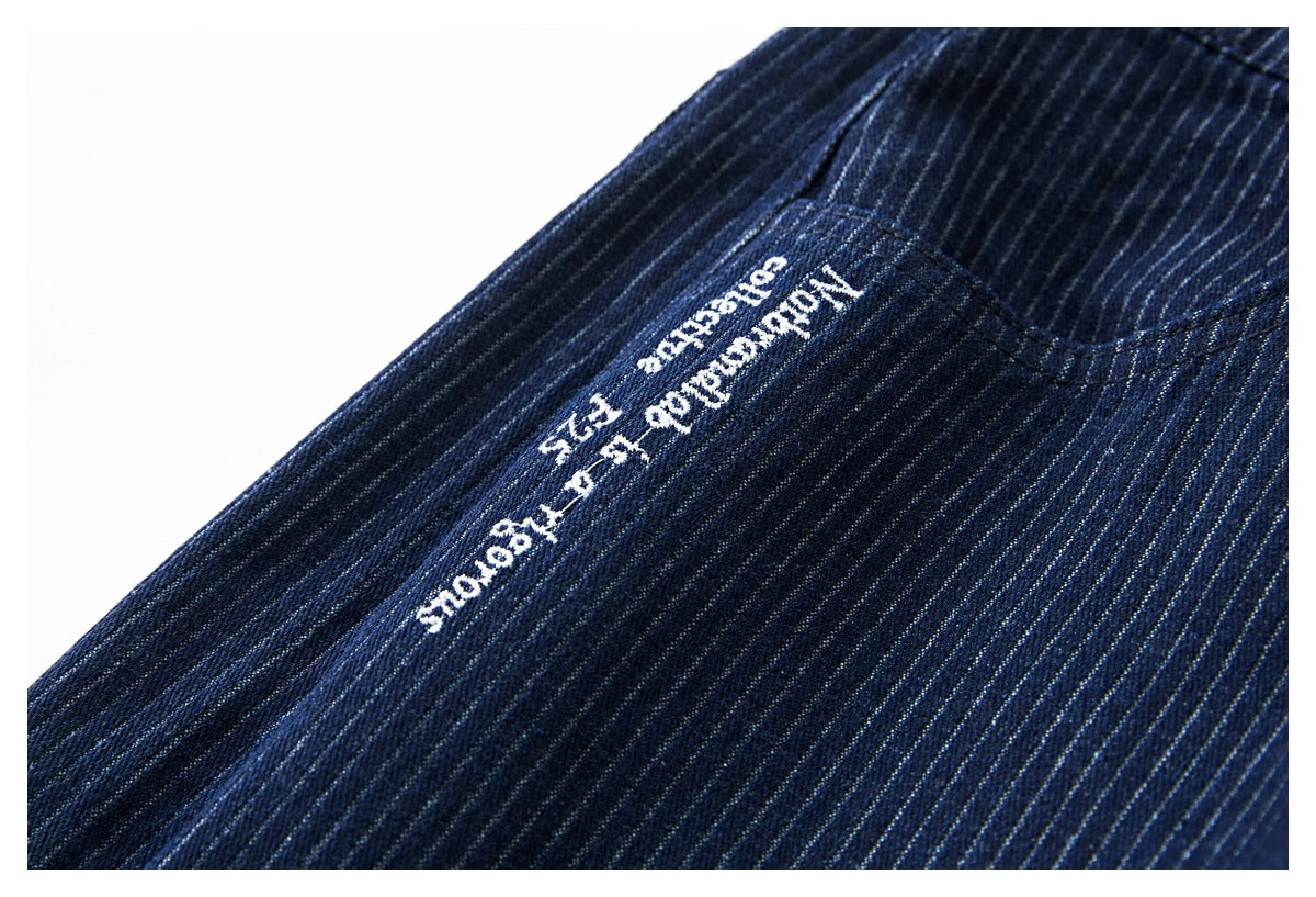 Close-up of dark navy pinstriped trousers with small white embroidered lettering.
