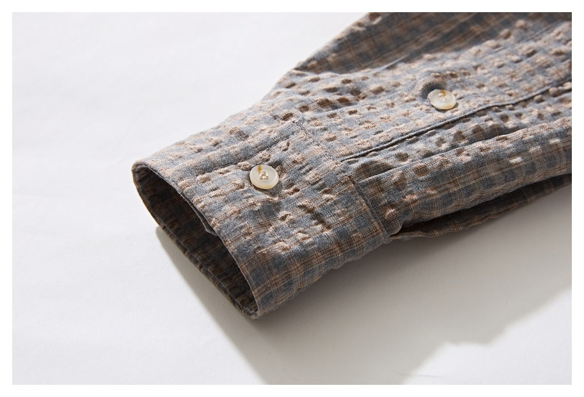 Close-up of the gray-brown patterned shirt cuff with two light buttons.