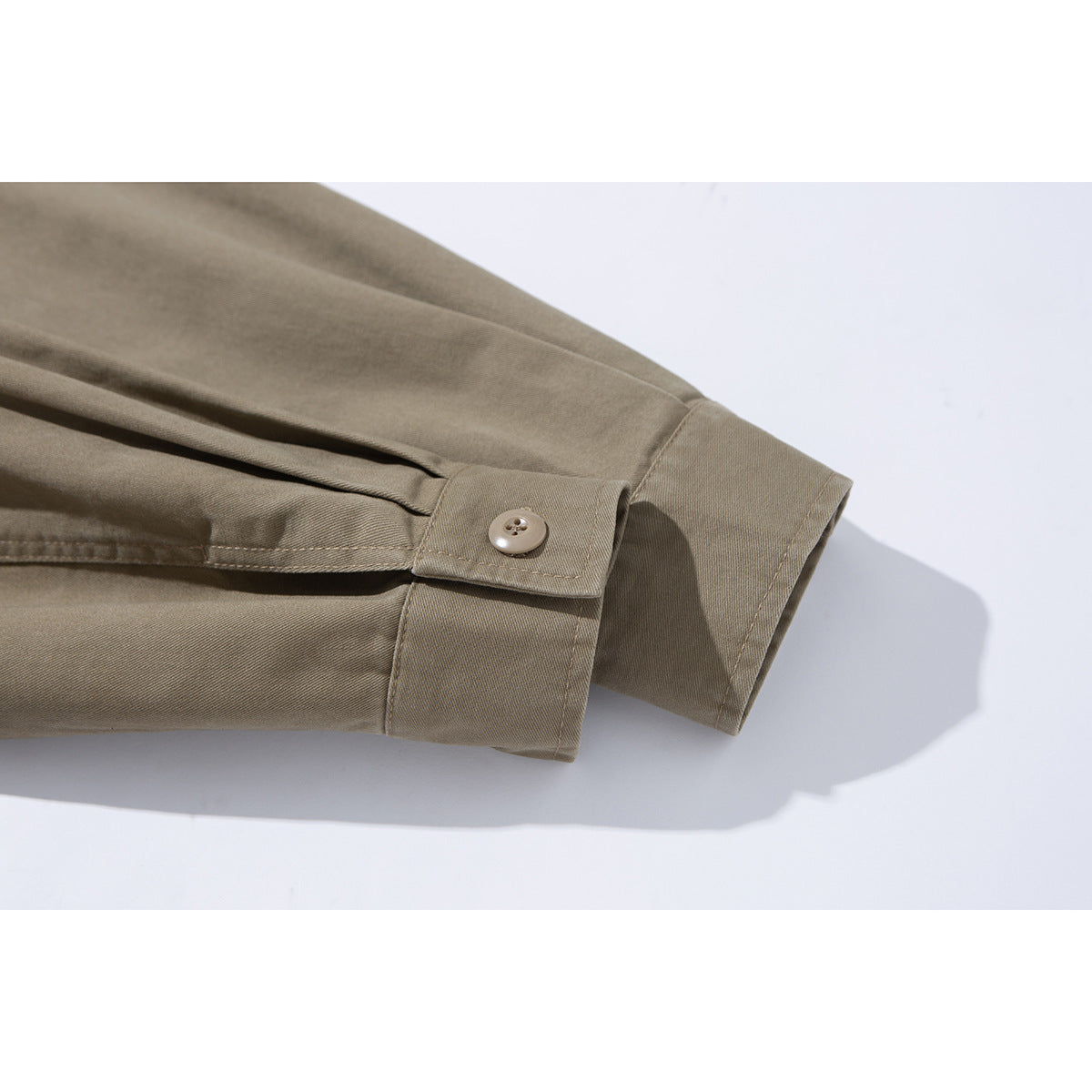 Close-up of a taupe jacket sleeve cuff with a buttoned tab and visible stitching.