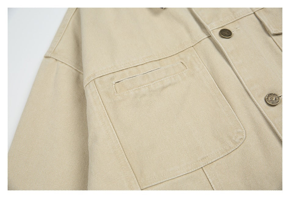 Close-up of a beige jacket's large patch pocket with a narrow welt opening and visible button placket.