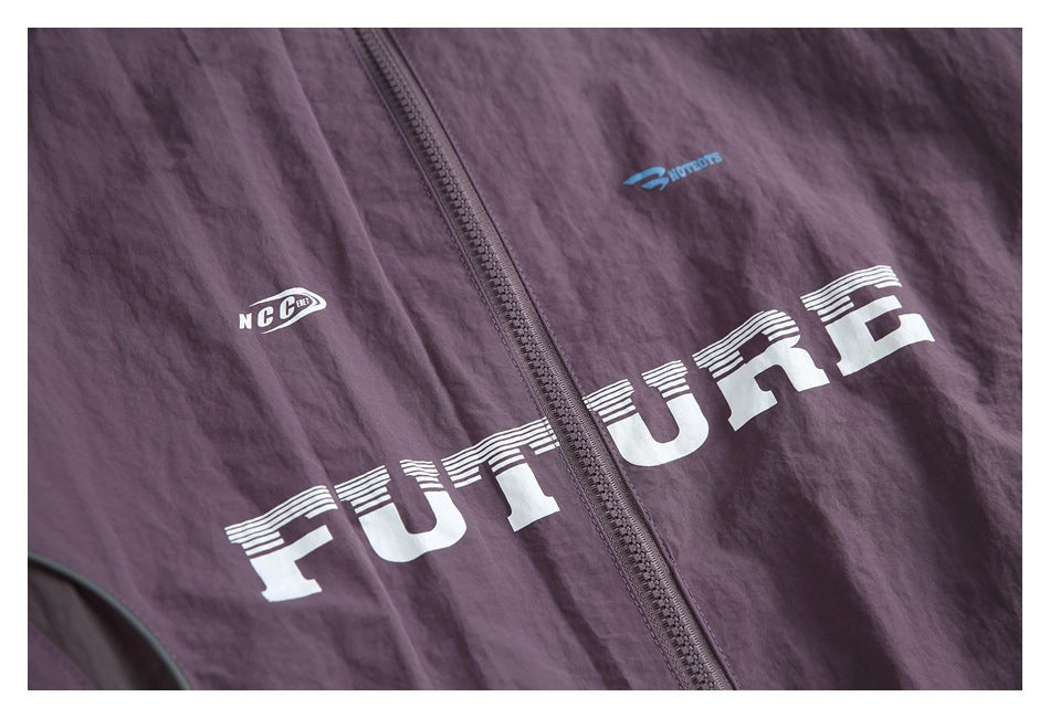 Close-up of the plum jacket's zipper and large white striped lettering with small chest graphics.