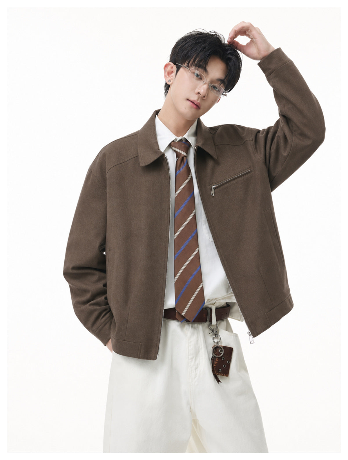 Model wearing an open dark brown collared jacket with a chest zip pocket over a white shirt and striped tie.