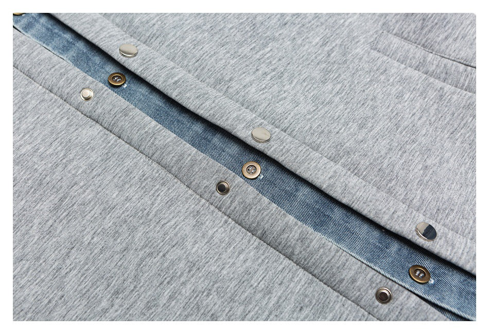 Close-up of the jacket's gray front placket, blue denim layer, and mixed metal snap fasteners.