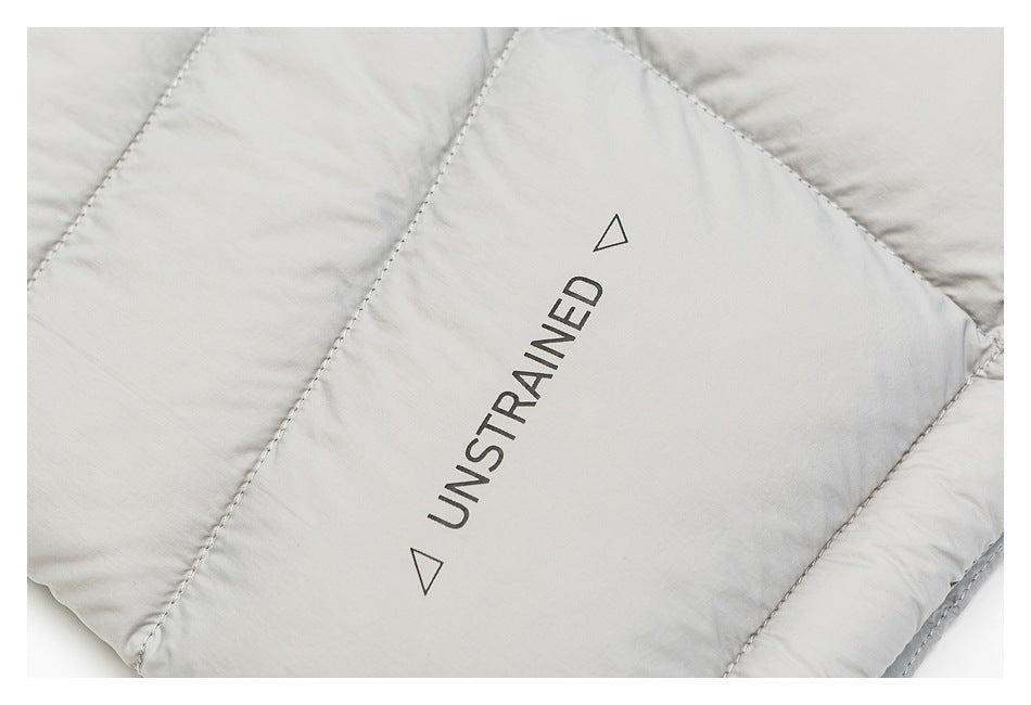 Close-up of black UNSTRAINED lettering printed on a light gray quilted jacket panel.